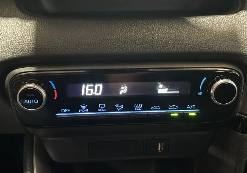 Détail du tableau de bord de la Toyota Yaris blanche 2021 montrant la commande de climatisation automatique à 16°C.