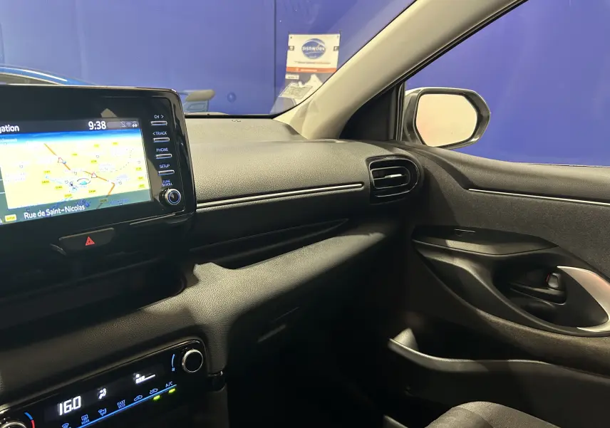 Vue intérieure côté passager de la Toyota Yaris 116h blanche, avec écran GPS et tableau de bord noir.