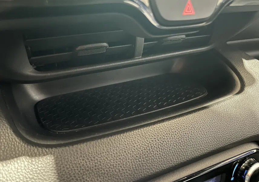 Détail de la console centrale noire de la Toyota Yaris 116h blanche, mettant en valeur un rangement avec surface antidérapante.
