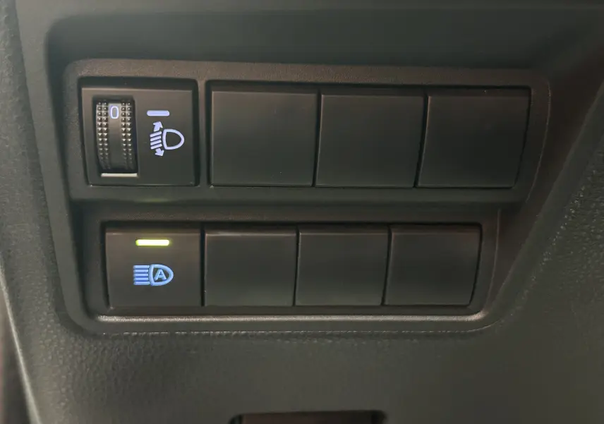 Gros plan sur les commandes d’éclairage du tableau de bord d’une Toyota Yaris blanche hybride 2021.
