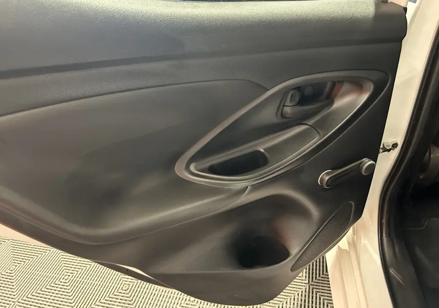 Vue rapprochée de la porte arrière droite noire intérieure d'une Toyota Yaris blanche 2021 avec poignée manuelle.