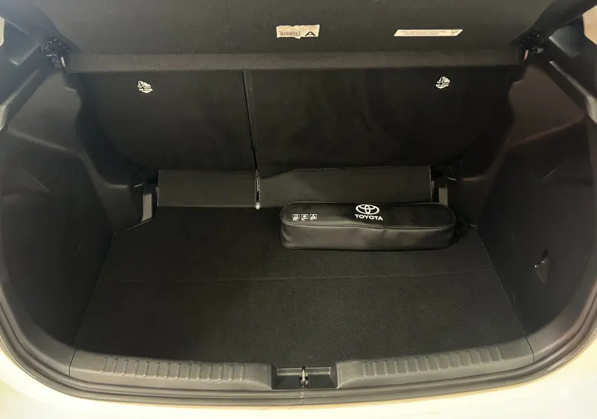 Vue du coffre ouvert d'une Toyota Yaris blanche 2021, avec un kit de secours Toyota noir posé à l'intérieur.