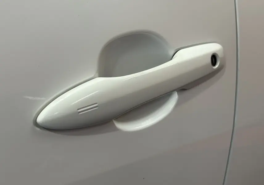Poignée de porte blanche en gros plan sur la porte côté gauche d'une Toyota Yaris 116h hybride 2021.