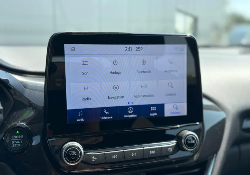 Écran tactile du système Ford SYNC 3 avec commandes vocales et bouton démarrage dans l'habitacle du Ford Puma gris Solar.