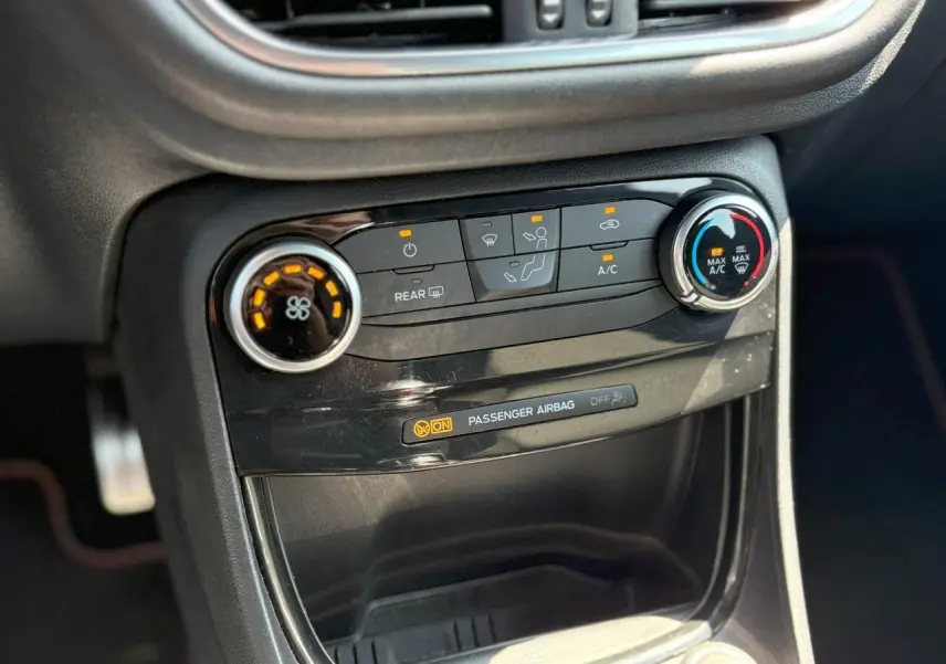 Vue rapprochée de la console centrale noire du Ford Puma ST Line 2020, avec commandes climatisation et témoin airbag passager.