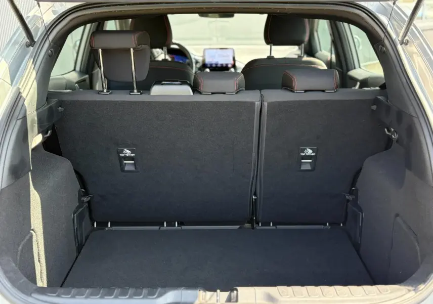 Coffre ouvert vu de l'arrière d'un Ford Puma gris Solar, montrant les sièges arrière et l'espace de chargement noir.