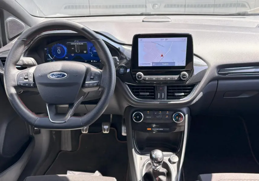 Vue intérieure frontale du tableau de bord du Ford Puma gris Solar, avec écran tactile GPS et volant ST-Line à surpiqûres rouges.