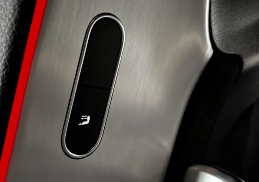 Détail du bouton de ventilation des sièges sur la console en aluminium brossé d'une Mercedes CLA 250 e AMG Line blanche.