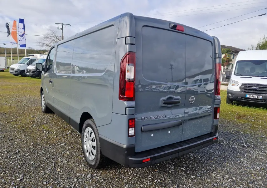 Vue 3/4 arrière droite du Nissan Primastar gris urbain 2025, fourgon utilitaire avec portes arrière fermées.
