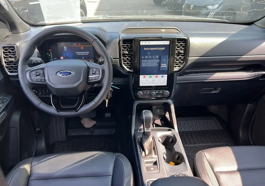 Vue intérieure du Ford Ranger 2025 montrant le tableau de bord noir avec écran tactile vertical et volant multifonctions.