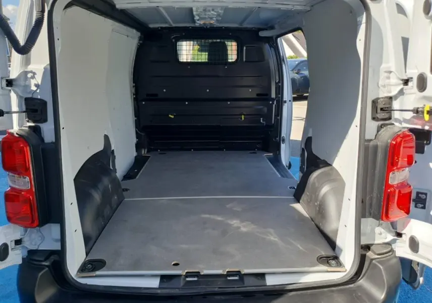 Vue arrière ouverte du Toyota Proace Fourgon blanc Glacier, montrant l'espace de chargement vide avec plancher bois et cloison pleine noire.