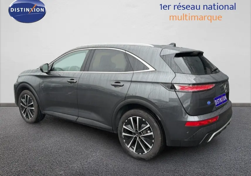 Vue 3/4 arrière droite d'un DS7 2024 gris titane métal avec jantes bi-ton et feux arrière LED allumés.