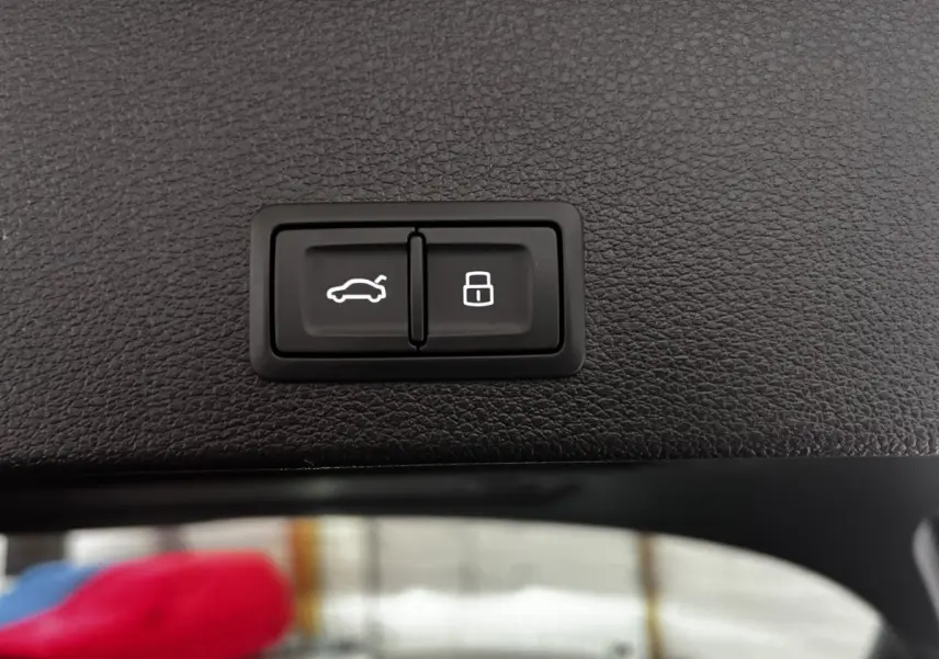 Gros plan sur les boutons d'ouverture de coffre et de verrouillage, intérieur noir texturé d'un Audi Q2 35 TFSI 2023.