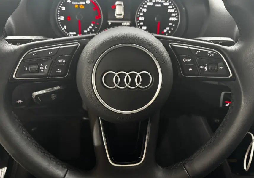 Vue rapprochée du volant cuir noir multifonctions d’un Audi Q2 35 TFSI 150 S Tronic S Line avec combiné d’instruments digital.