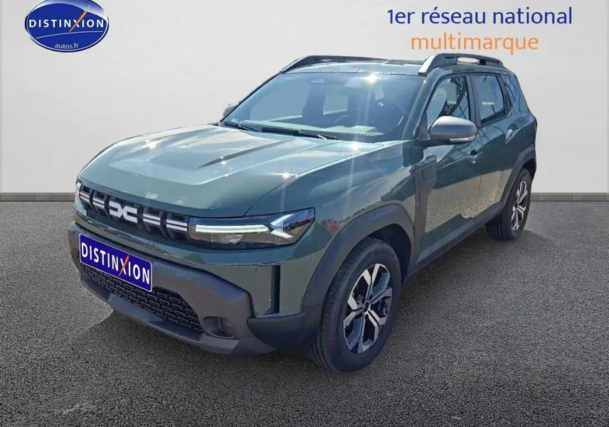 Vue 3/4 avant d’un Dacia Duster vert kaki 2025 avec barres de toit et jantes alu distinctives.