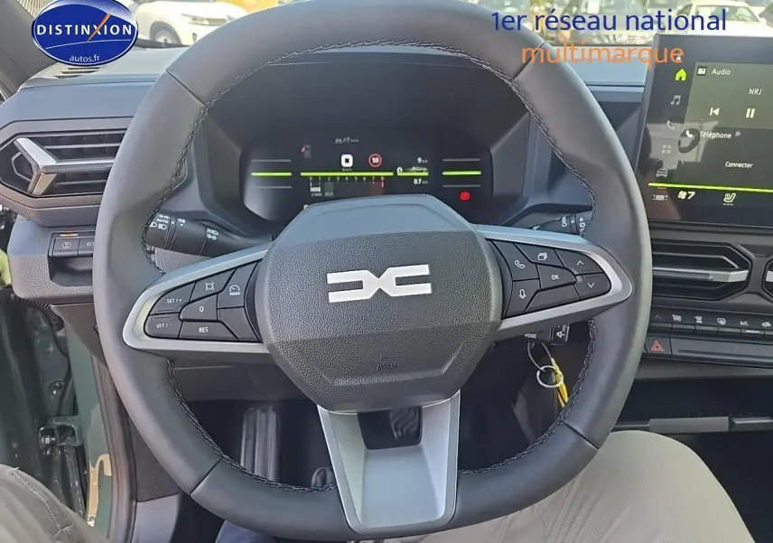Vue intérieure centrée sur le volant multifonction du Dacia Duster vert kaki avec tableau de bord numérique et écran tactile.