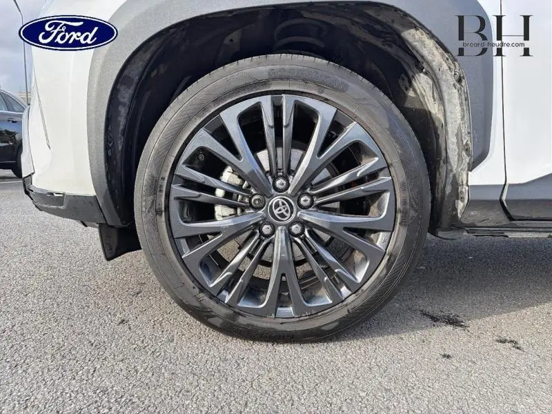 Gros plan sur la roue avant droite avec jante alliage noire du Toyota Yaris Cross blanc nacré.