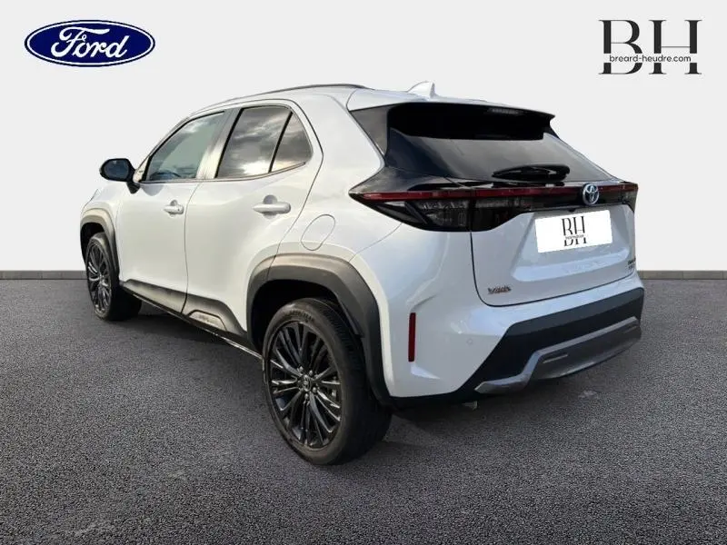 Toyota Yaris Cross blanc nacré vue 3/4 arrière droit, avec jantes noires et feux arrière LED sombres.