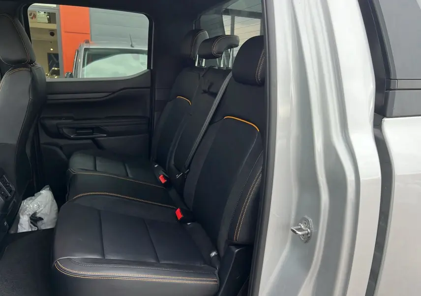 Vue intérieure côté gauche sur les sièges arrière noirs avec surpiqûres orange du Ford Ranger gris iconic 2025 Wildtrak X.