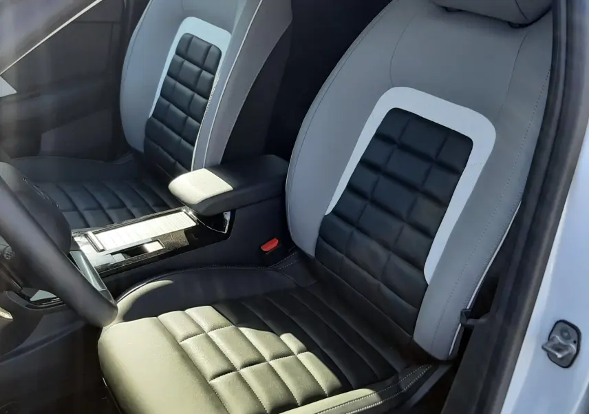 Vue intérieure rapprochée des sièges avant en cuir noir et gris de la Citroën C4 1.2 Hybrid 2025 blanche.