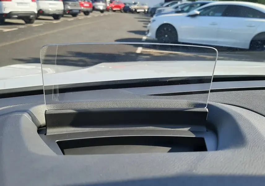 Vue depuis l'intérieur d'une Citroën C4 blanche 2025, mettant en valeur le pare-brise avec affichage tête haute transparent.