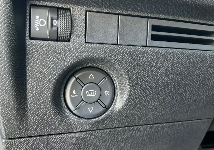 Détail du tableau de bord côté gauche de la Citroën C4 blanche, avec commande de réglage des phares et du tableau de bord.