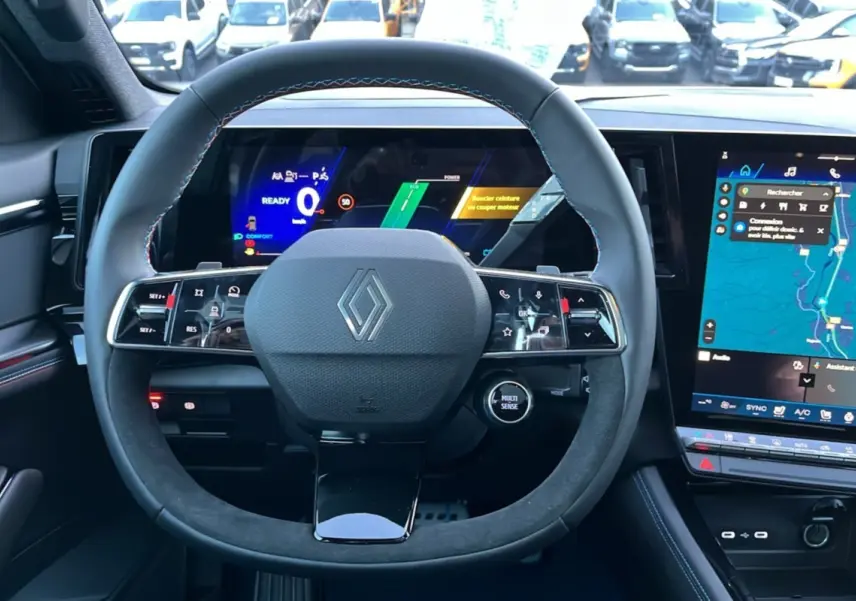 Vue frontale du volant cuir et alcantara avec logo Renault, tableau de bord numérique et écran tactile du Renault Rafale 2025.