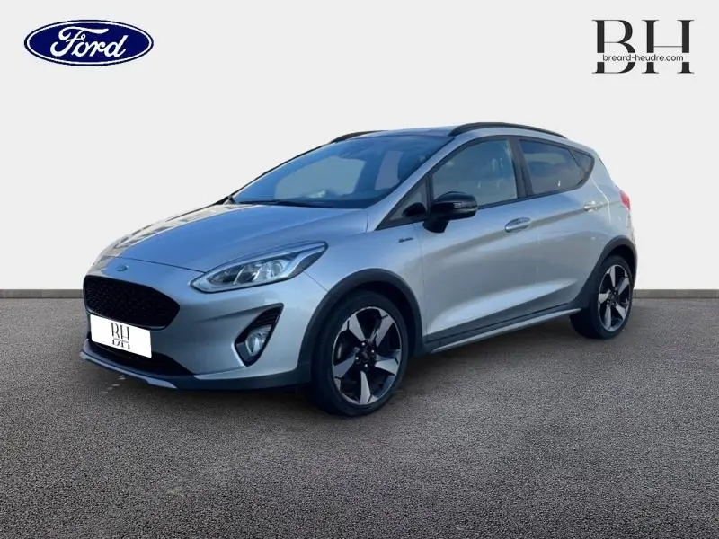 Vue 3/4 avant droit d'une Ford Fiesta 1.0 EcoBoost gris lunaire avec jantes alliage et barres de toit noires.