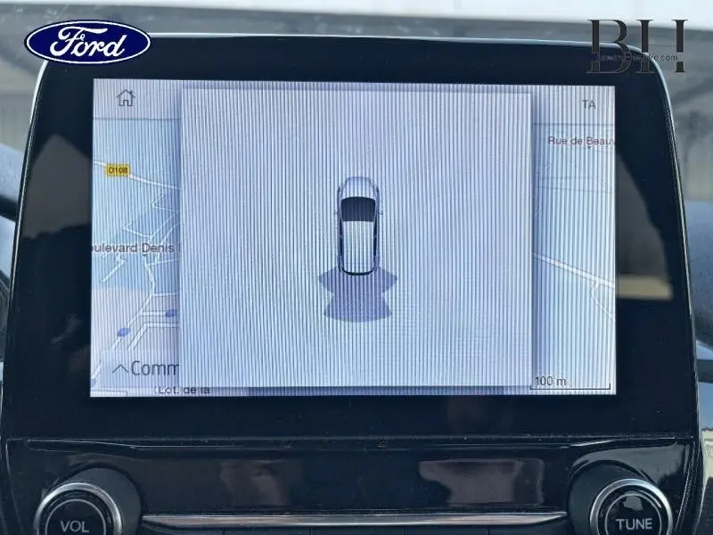 Écran tactile central montrant la vue aérienne de la Ford Fiesta gris lunaire avec carte GPS en arrière-plan.