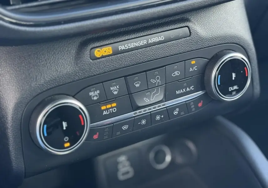 Gros plan sur la console de climatisation avec commandes chauffantes et affichage digital, intérieur noir du Ford Kuga.
