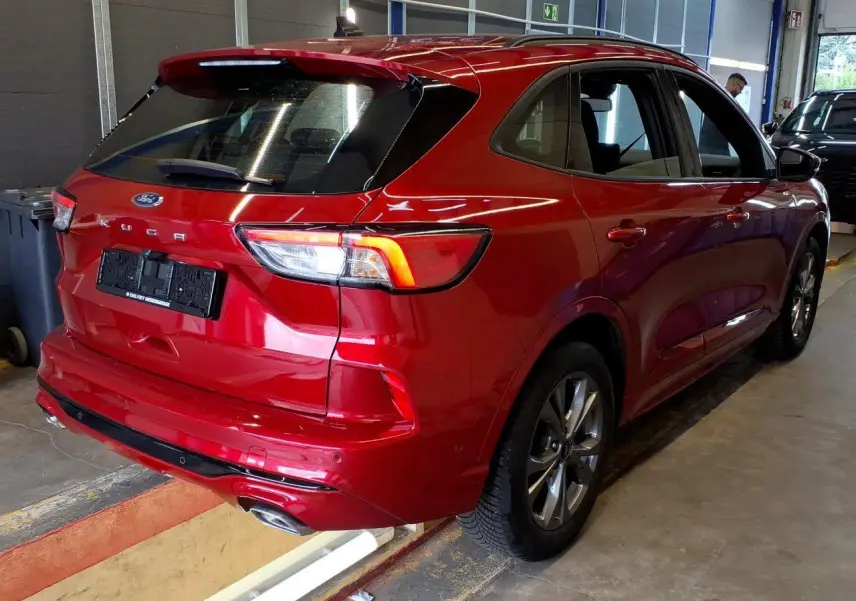 Vue 3/4 arrière droite du Ford Kuga rouge Lucifer 2024 avec double sortie d’échappement et jantes alliage 18 pouces.
