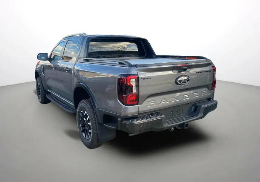 Ford Ranger 2025 gris carbone vu 3/4 arrière droit avec rideau de benne et jantes noires distinctives.
