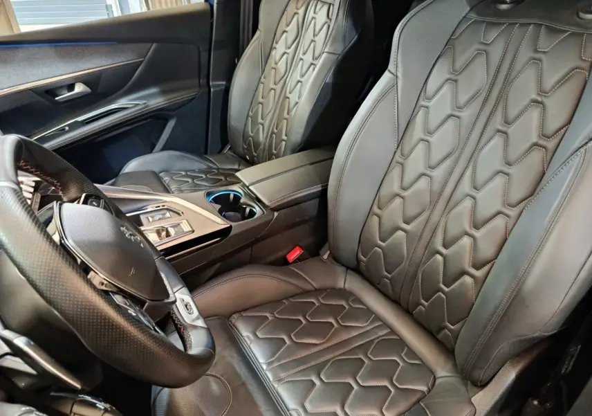 Vue intérieure côté conducteur du Peugeot 3008 GT Pack 1.6 Hybrid 225, sièges cuir noir avec surpiqûres géométriques.