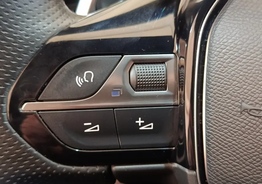 Gros plan sur les commandes vocales et volume au volant cuir noir du Peugeot 3008 bleu hybride rechargeable.