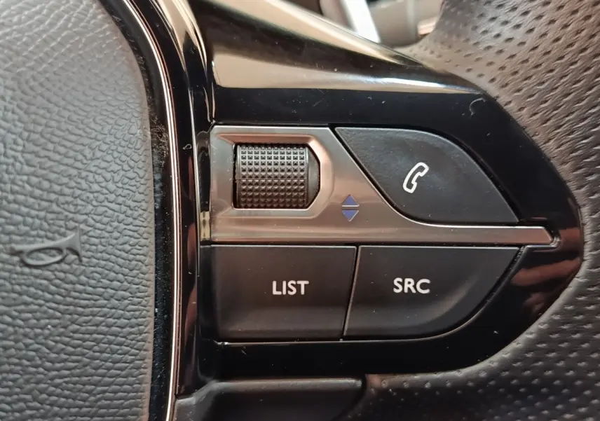 Gros plan sur les commandes gauche du volant cuir perforé du Peugeot 3008 bleu hybride rechargeable.