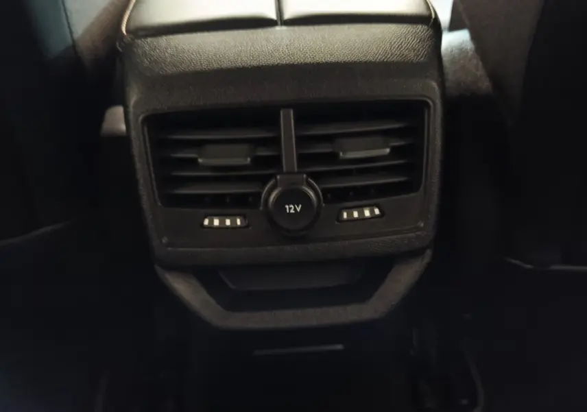 Gros plan sur la sortie d'air arrière avec prise 12V du Peugeot 3008 hybride bleu, intérieur sombre.
