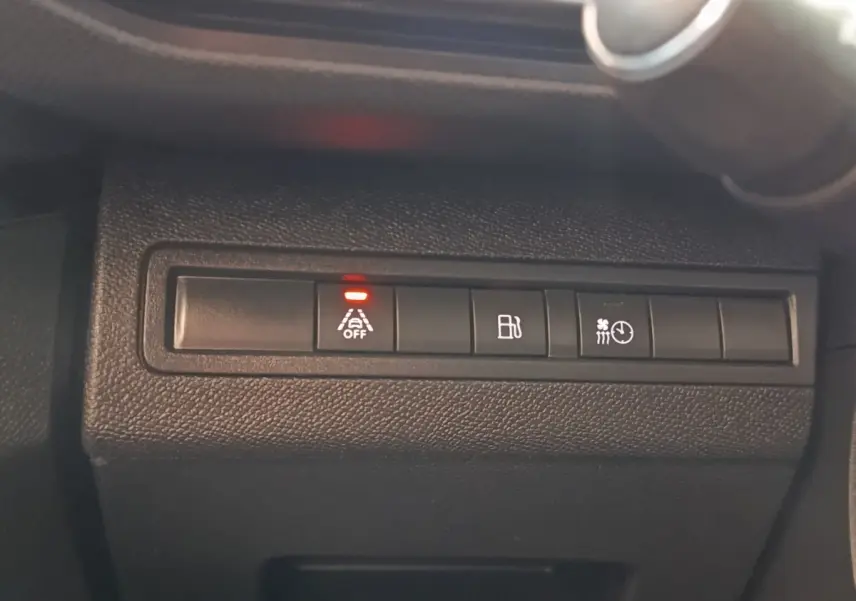 Gros plan sur les boutons de commande noirs du tableau de bord du Peugeot 3008 bleu, avec témoin rouge allumé.