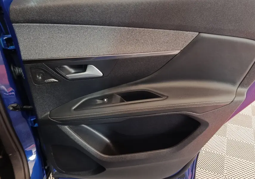 Vue intérieure côté gauche de la porte avant bleu du Peugeot 3008 hybride avec garniture tissu et cuir noir.