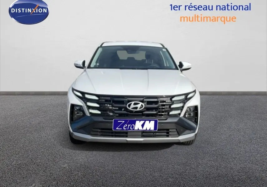 Vue frontale d'un Hyundai Tucson blanc Atlas avec calandre noire et feux LED distinctifs.