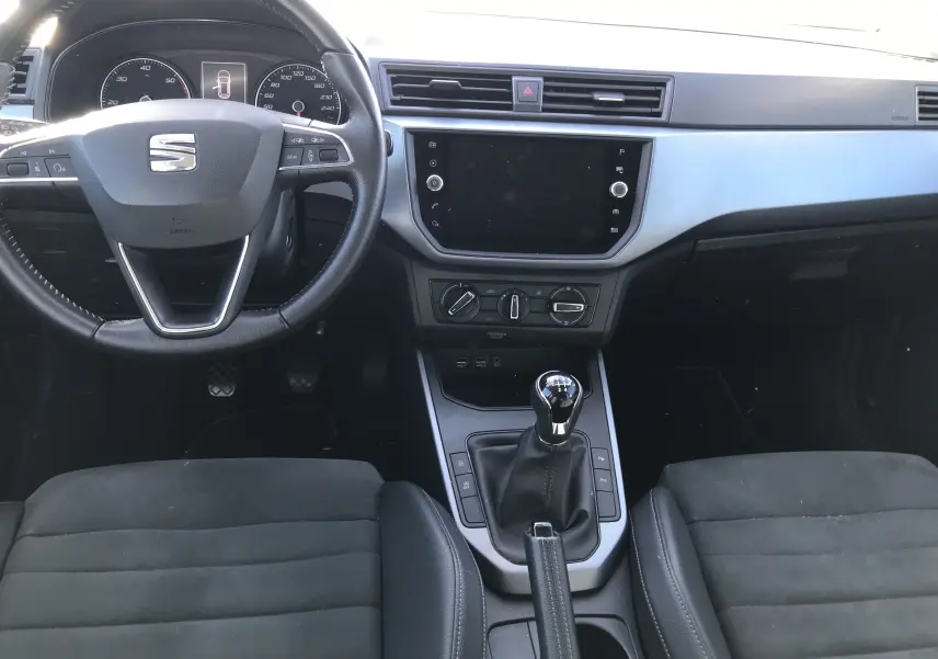 Intérieur de la SEAT Arona 2019 vue de face, tableau de bord noir avec volant cuir et levier de vitesse manuel.