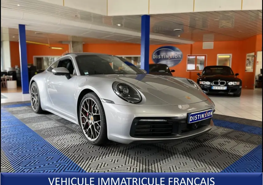 Porsche 911 (992) Carrera S argent GT vue 3/4 avant droit, jantes RS Spyder et intérieur noir visible en showroom