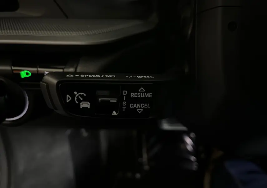 Gros plan sur la commande de régulateur de vitesse au volant d'une Porsche 911 Carrera S argent GT, intérieur noir.