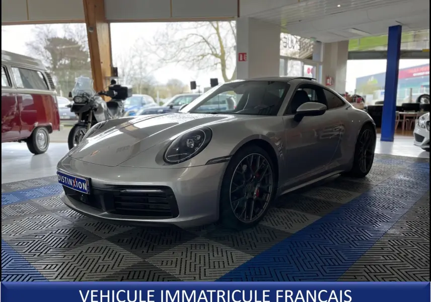 Porsche 911 Carrera S argent GT vue 3/4 avant droit en intérieur, avec jantes RS Spyder et détails sportifs visibles.