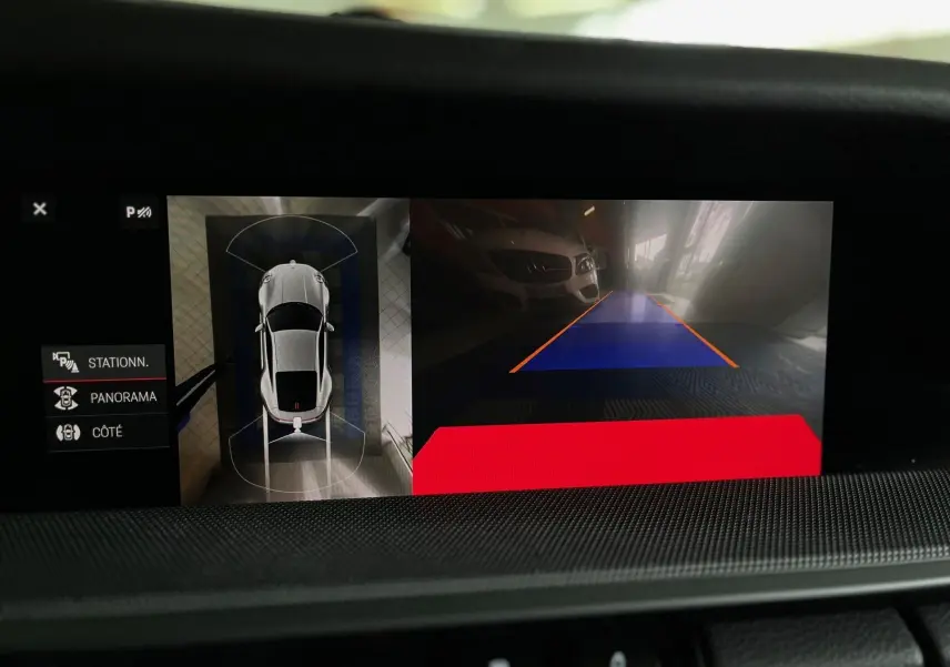 Affichage écran intérieur montrant la vue aérienne et caméra de recul d'une Porsche 911 argent GT en stationnement.