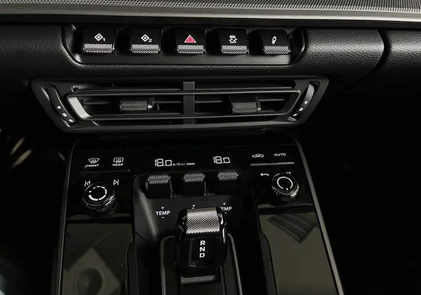 Gros plan sur la console centrale noire brillante de la Porsche 911 992 Carrera S avec levier de vitesses et commandes climatiques.