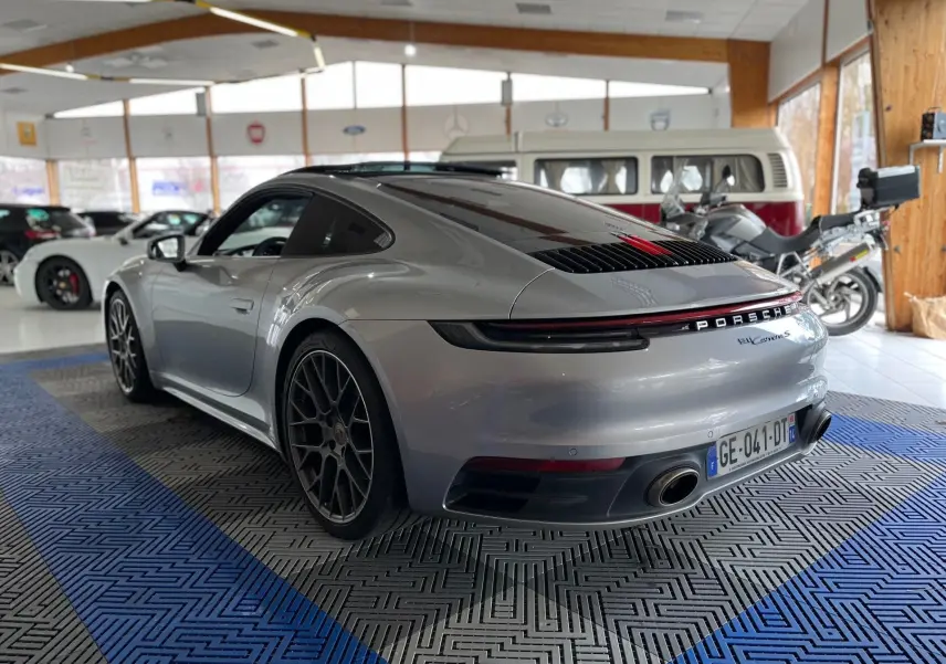 Vue 3/4 arrière droite d'une Porsche 911 Carrera S 2019 argent GT avec jantes RS Spyder en intérieur showroom.