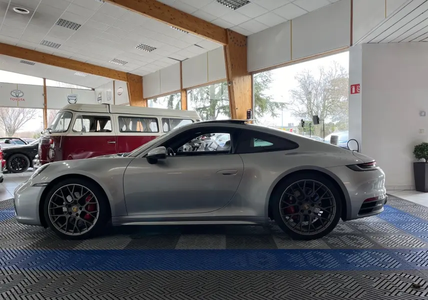 Profil côté gauche de la Porsche 911 Carrera S 2019 en argent GT avec jantes RS Spyder et intérieur noir visible en showroom.