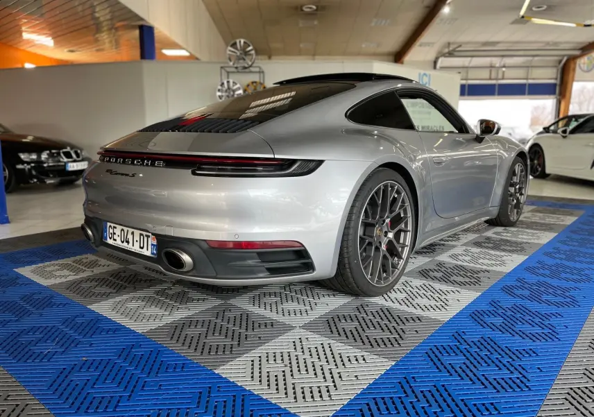 Vue 3/4 arrière droite d'une Porsche 911 Carrera S 2019 argent GT avec jantes RS Spyder en intérieur showroom.