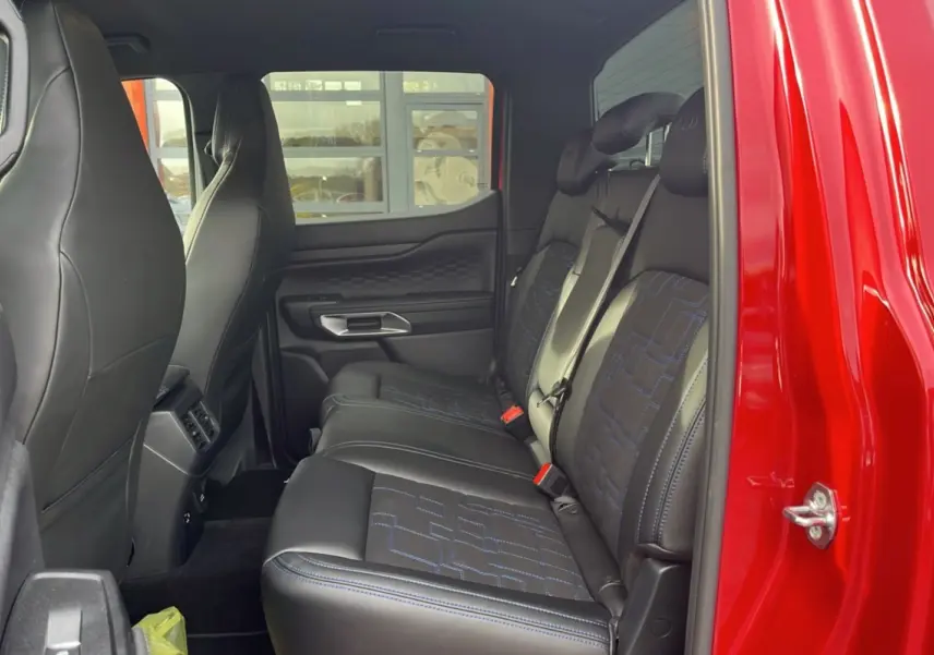 Vue latérale intérieure sur les sièges arrière en cuir noir avec surpiqûres bleues du Ford Ranger 3.0 V6 Lucid Red 2025.