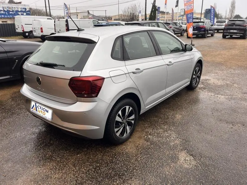 Vue 3/4 arrière droite d'une Volkswagen Polo gris Urano avec jantes alu et feux arrière foncés sur parking.